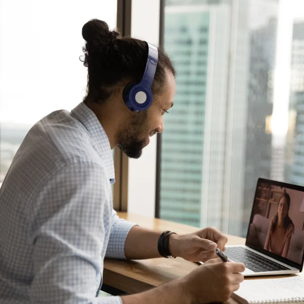 Un homme portant des écouteurs, utilisant un ordinateur portable, concentré sur son travail.