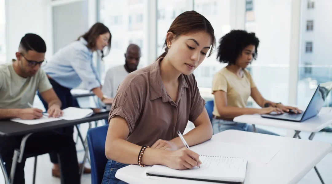 Un groupe d'étudiants dans une salle de classe en train d'écrire sur des cahiers.