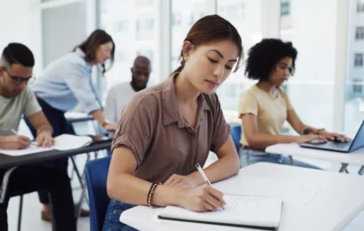 Un groupe d'étudiants dans une salle de classe en train d'écrire sur des cahiers.