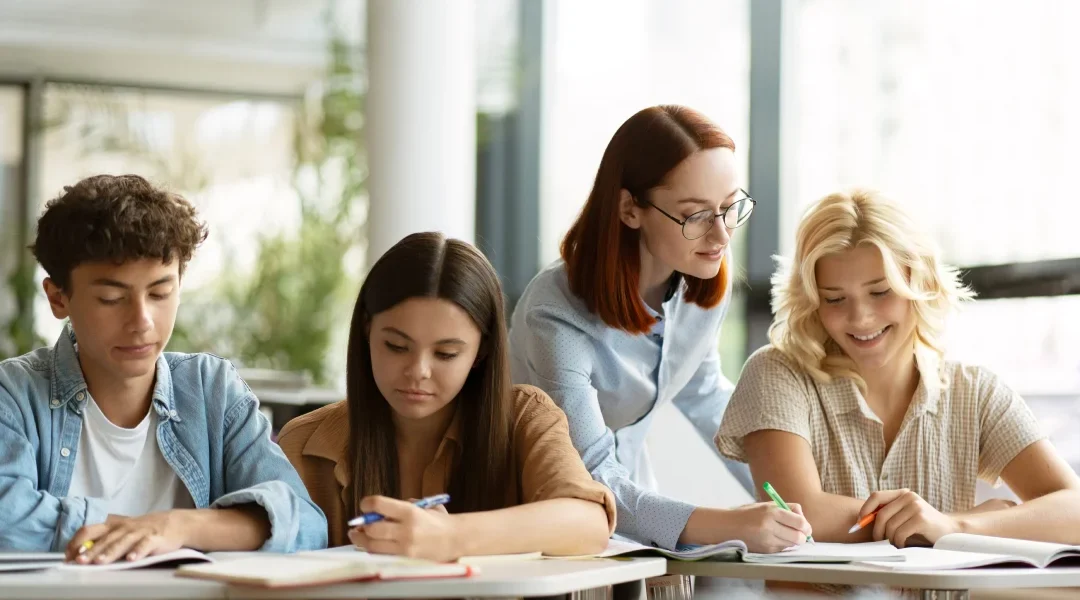 Un groupe d'étudiants concentrés sur leurs études dans une salle de classe, entourés de livres et de matériel scolaire.