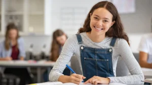 Une jeune fille, le sourire aux lèvres, prend des notes dans son carnet.