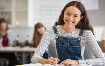 Une jeune fille, le sourire aux lèvres, prend des notes dans son carnet.