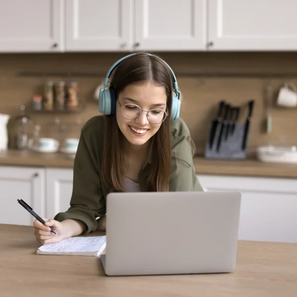 Une femme portant des écouteurs, concentrée sur son ordinateur portable.