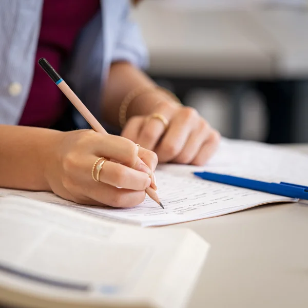 Une femme écrit sur une feuille de papier avec un stylo.